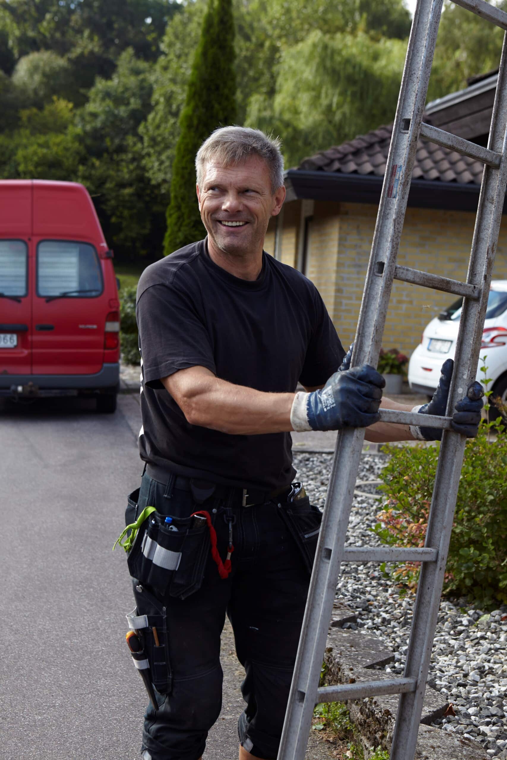 En glad medarbetare som håller i en stege